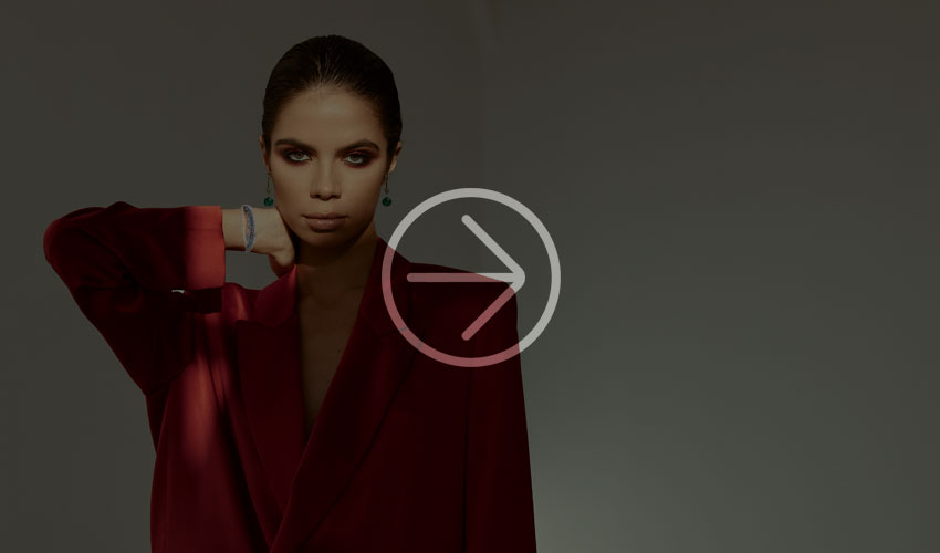 Woman in a mint green pleated dress lies on a velvet sofa, wearing turquoise jewelry.