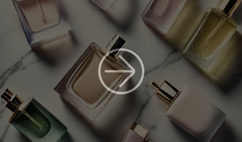 Several perfume bottles with pastel-colored liquids on a white marble surface.