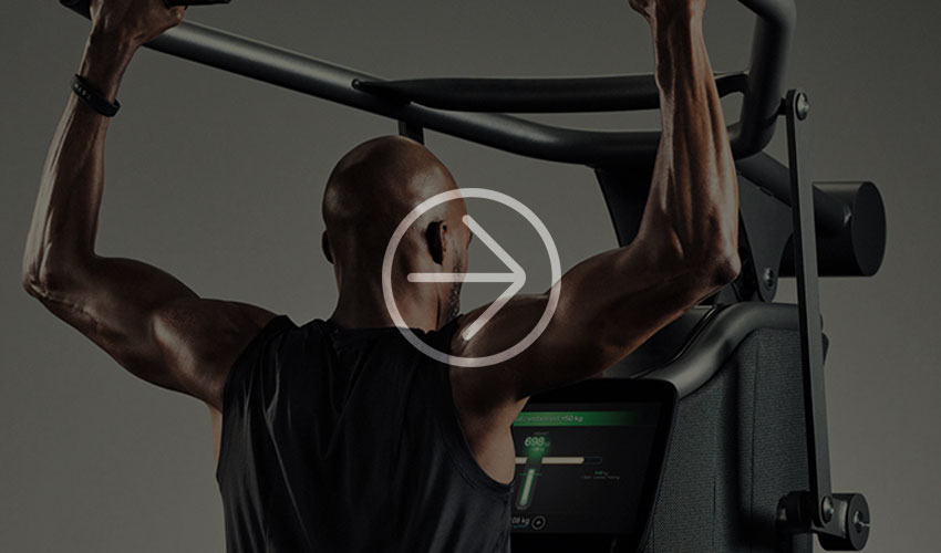 Man does a pull-up on a fitness machine, displaying strength and concentration.