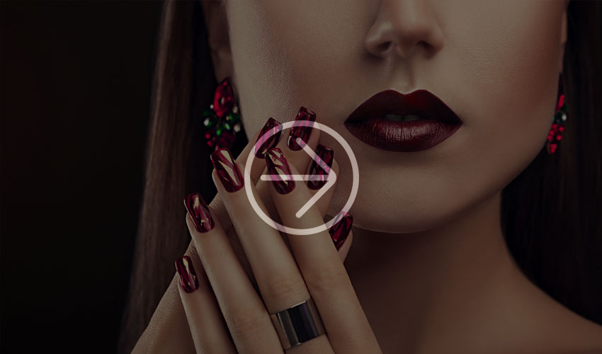 Woman with long dark red fingernails and matching lipstick.