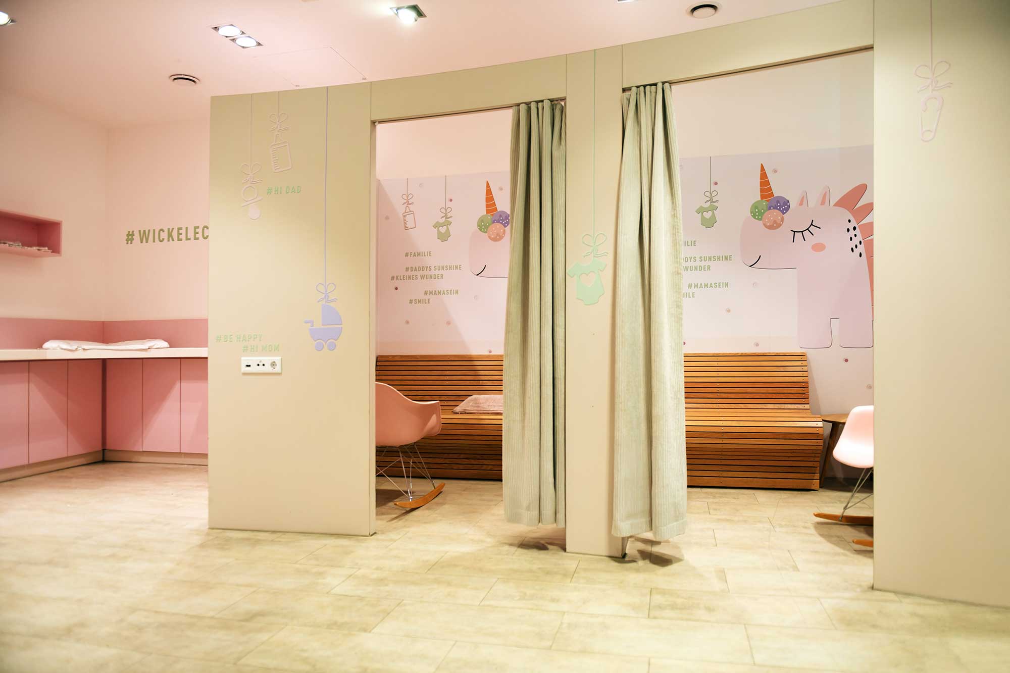 Bright and playful changing room in pastel colors, featuring unicorn wall murals and cozy seating areas for parents.