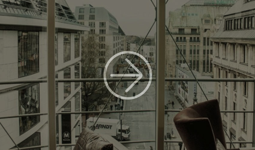 View from a modern balcony onto a city street with contemporary buildings and hustle and bustle below.